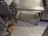 a stainless steel table in a kitchen with a hose on the floor