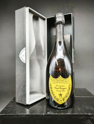 une bouteille de champagne dans un coffret, posée sur une table devant un fond noir et blanc