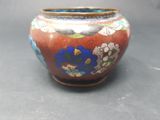 a red vase with blue flowers on it sitting on a table