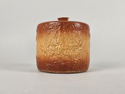 un vase marron et orange avec un couvercle, posé sur une table