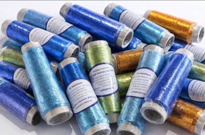 a bunch of spools of metallic thread on a white surface