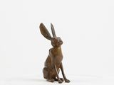 a bronze statue of a rabbit sitting on a white surface
