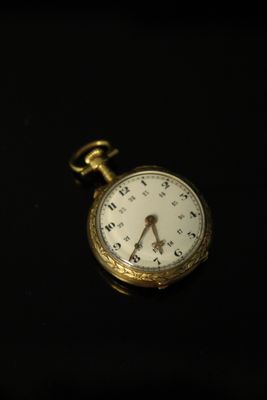 a gold pocket watch on a black surface