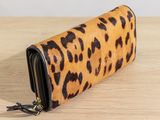 the leopard print wallet purse is on a wooden table