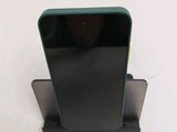 a black cell phone on a stand on a white surface