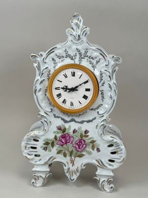 une horloge blanche ornée de fleurs roses, posée sur un socle