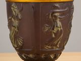 a brown vase with gold decoration on it on a wooden table