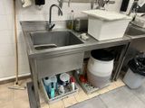 a sink in the middle of a kitchen with a trash can underneath it