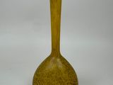 un vase jaune posé sur une surface blanche