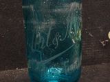 a blue glass bottle sitting on a black surface