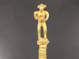 une figurine en or représentant un homme tenant un poisson au bout d'un bâton