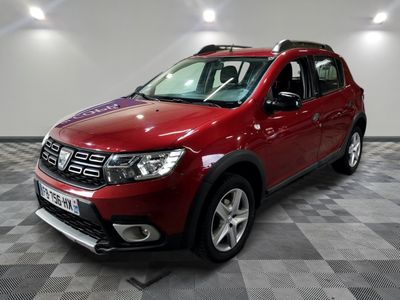La Dacia rouge est garée sur un sol en carrelage à damier.