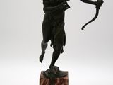 statue en bronze représentant un homme avec un arc et des flèches, posée sur un socle en marbre