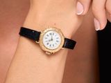 woman wearing a gold watch with a white dial on her wrist