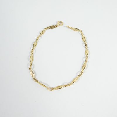 gros plan d'un bracelet en or sur une surface blanche