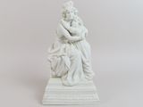 statue blanche représentant une femme tenant un enfant dans ses bras, posée sur un socle