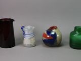 trois vases et une cruche sont posés sur une surface blanche
