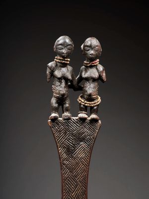 une statue en bronze représentant deux personnages debout au sommet d'un vase
