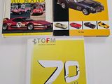 three ferrari books on a white table with a yellow background