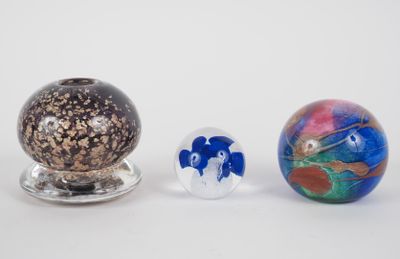 three different colored glass balls sitting next to each other on a white surface