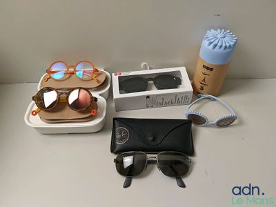 une boîte de lunettes de soleil, une tasse de café et une paire de lunettes de soleil posées sur une table