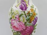 a vase with flowers painted on it sitting on a table