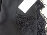 black pants with fringes and tags on them sitting on a table
