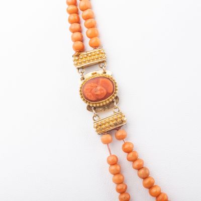a close up of an orange beaded necklace on a white surface