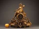 a gold clock sitting on top of a table next to an orange