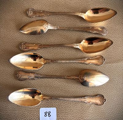 six silver spoons are lined up on a table with a price tag