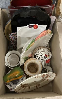 une boîte remplie d'assiettes et de tasses posée par terre