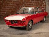 a red car that is parked in front of a brick wall