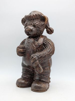 wooden statue of a boy holding a teddy bear in his arms