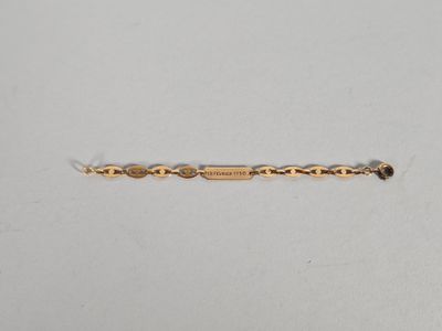 gros plan d'un bracelet en or sur une surface blanche