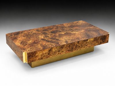 une grande table basse rectangulaire avec un piètement en laiton et un plateau en marbre marron