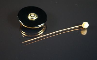 un objet noir et doré posé sur une surface noire, à côté d'une paire de ciseaux