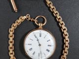 une montre de poche attachée à une chaîne, posée sur une table