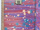 a hand holding an open book with a picture of planets on it