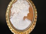 Une broche plaquée or représente le profil d'une femme.