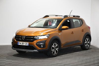 Une voiture orange est garée dans une pièce au sol à carreaux.