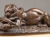 bronze statue of a lion laying on a rock with a bird in it ' s mouth