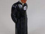 une figurine représentant un homme vêtu d'un manteau noir et d'un chapeau