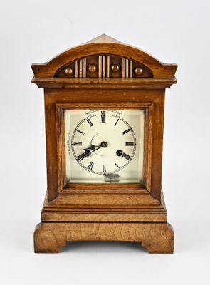 a small wooden clock with roman numerals on the face