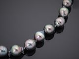 a close up of a pearl necklace on a black surface
