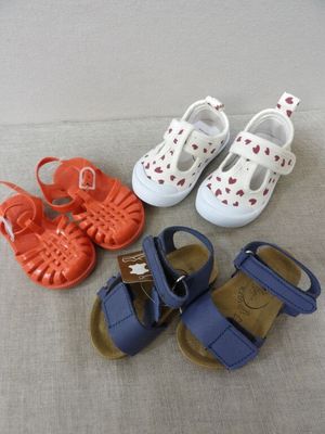 four pairs of baby shoes on a bed