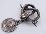 a close up of a metal snake with a coin on a white surface