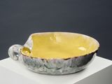 yellow and gray bowl with handle on white pedestal