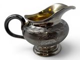 silver plated gravy with a black handle on a white background