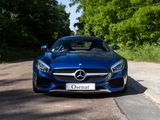 the front of a blue mercedes sports car driving down a country road