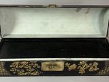 une vieille boîte noire et dorée ornée de fleurs dorées